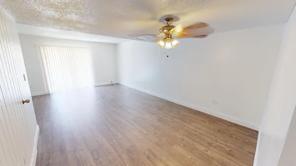 a view of a room with wooden floor and ceiling fan