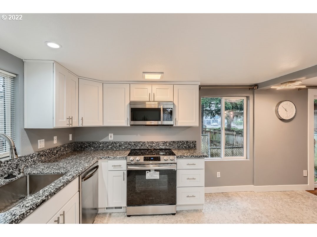 12603 Southeast Foster Road Portland, OR 97236 - Photo 11 of 28 a kitchen with stainless steel appliances granite countertop a stove a sink and a microwave