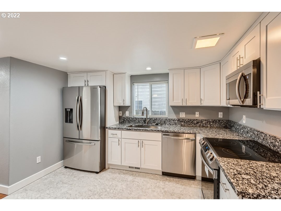 12603 Southeast Foster Road Portland, OR 97236 - Photo 13 of 28 a kitchen with a sink a refrigerator and cabinets