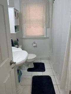 a bathroom with a sink a toilet a window and mirror