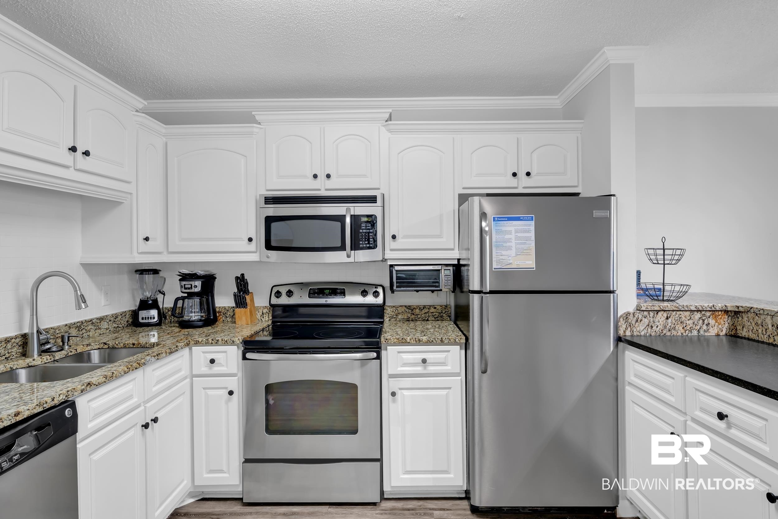 400 Plantation Road, Unit 2118 Gulf Shores, AL 36542 - Photo 11 of 59 Kitchen featuring white cabinetry, stainless steel appliances, granite-style countertops, double basin stainless steel sink, and wood-finish flooring