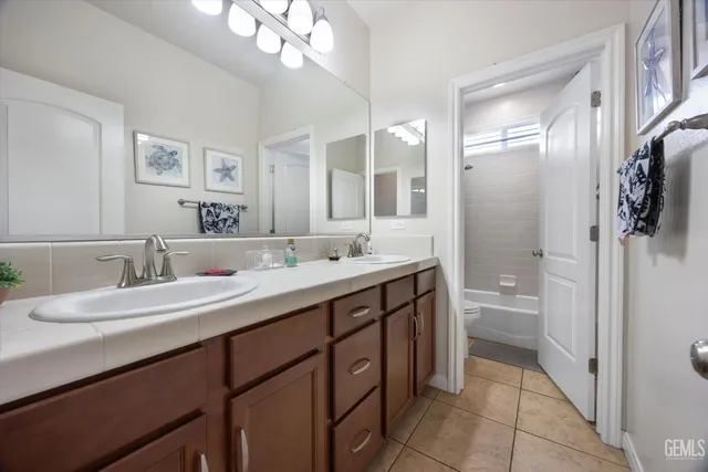a spacious bathroom with a double vanity sink toilet mirror and shower