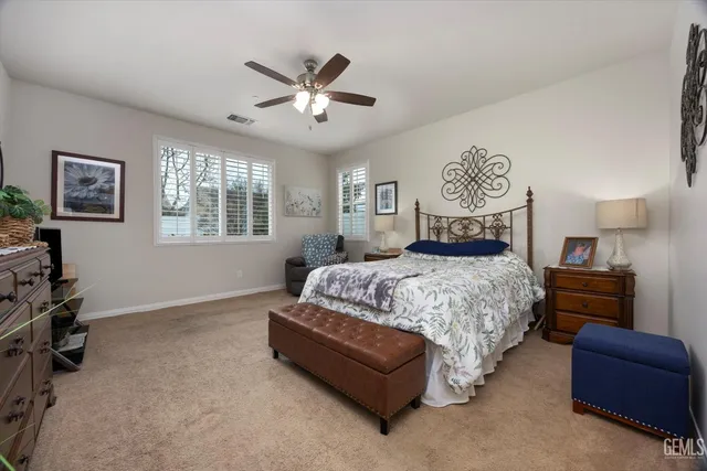 a bedroom with a bed couches and windows