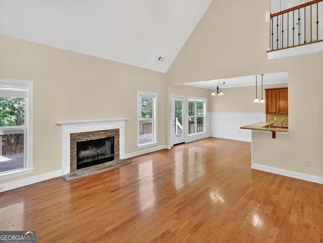 an empty room with wooden floor fireplace and windows