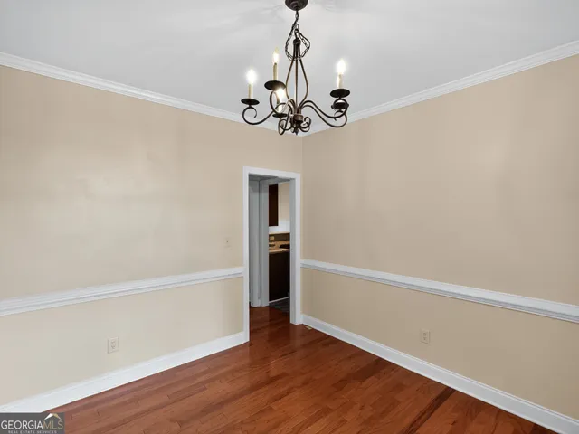 a view of an empty room with wooden floor and windows