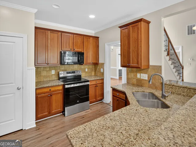 a kitchen with granite countertop a stove sink and a microwave