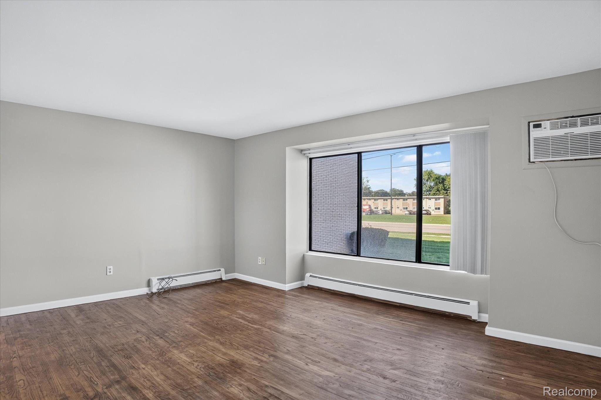 32650 Mound Road, Unit 4 Warren, MI 48092 - Photo 7 of 32 Wood-finish flooring, light grey wall paint, and a large window with vertical blinds
