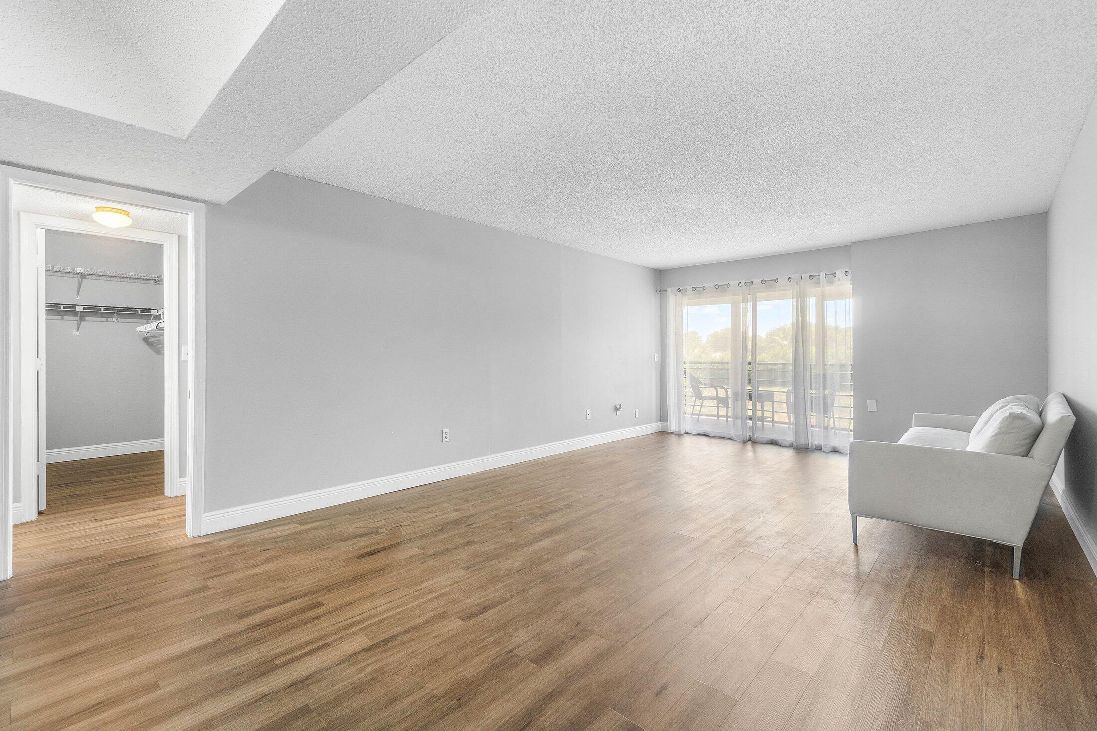 23395 Carolwood Lane, Unit 207 Boca Raton, FL 33428 - Photo 18 of 39 an empty room with wooden floor and windows