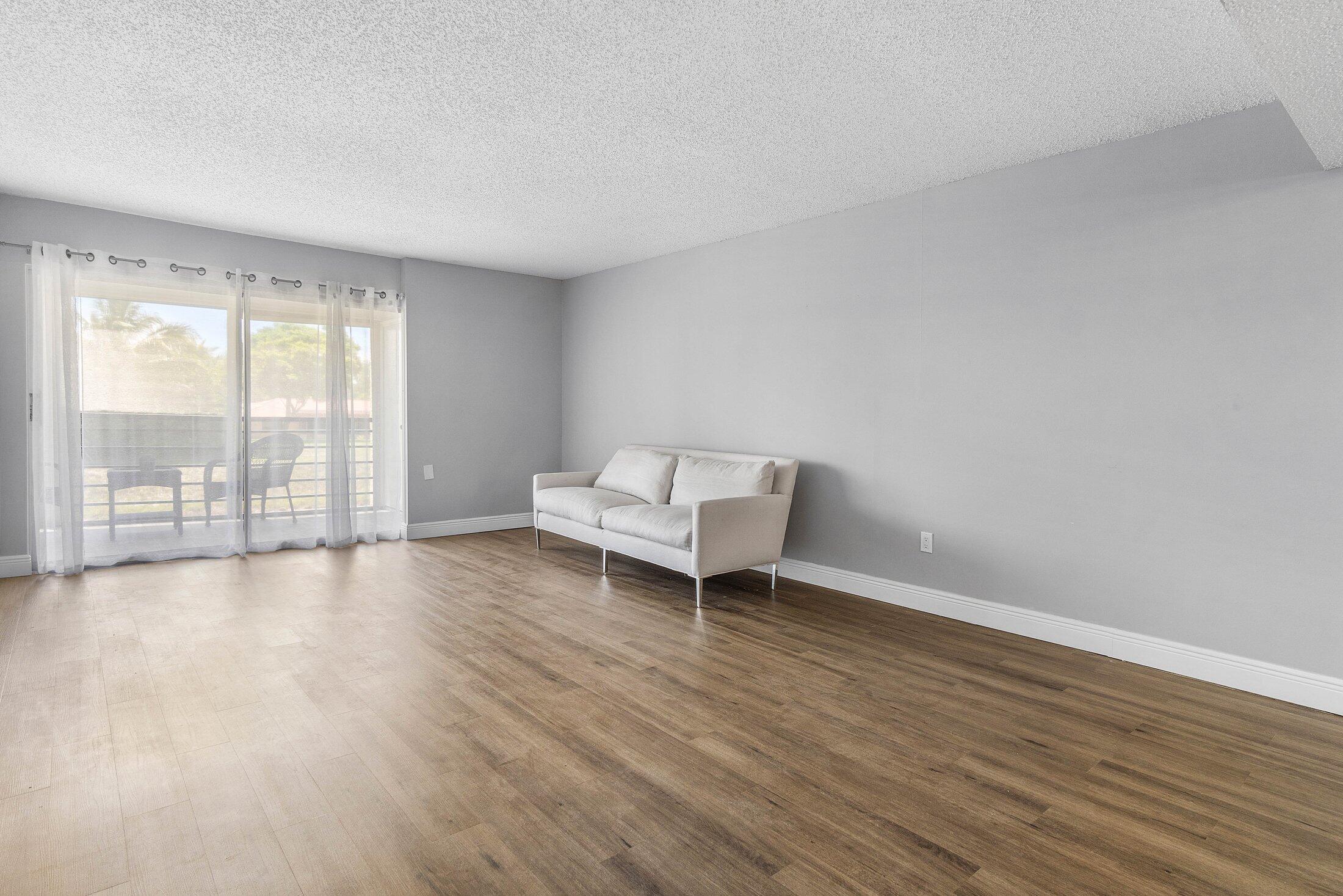 23395 Carolwood Lane, Unit 207 Boca Raton, FL 33428 - Photo 19 of 39 a view of an empty room with wooden floor and a window