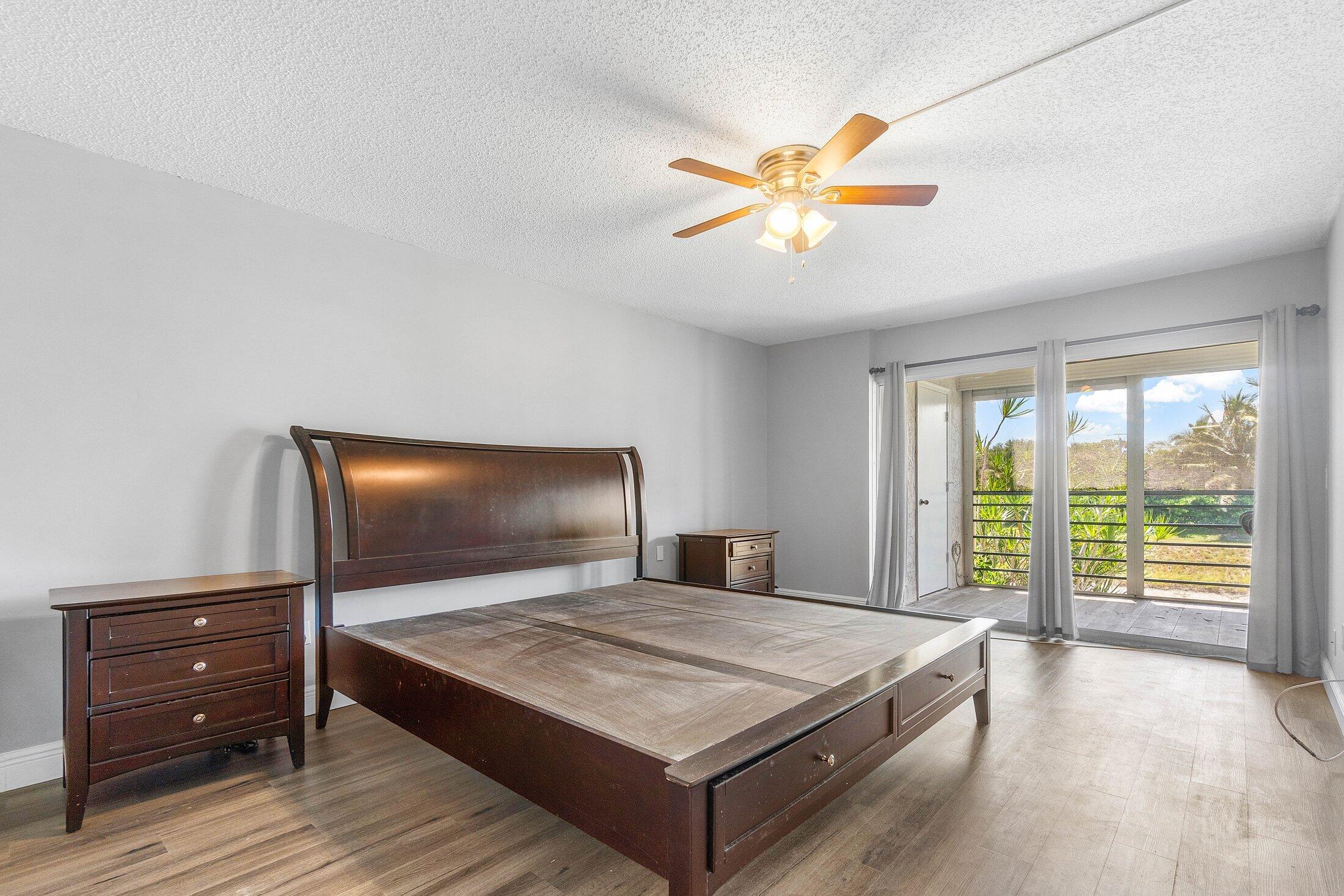 23395 Carolwood Lane, Unit 207 Boca Raton, FL 33428 - Photo 22 of 39 a bedroom with a bed and a flat tv screen on dresser