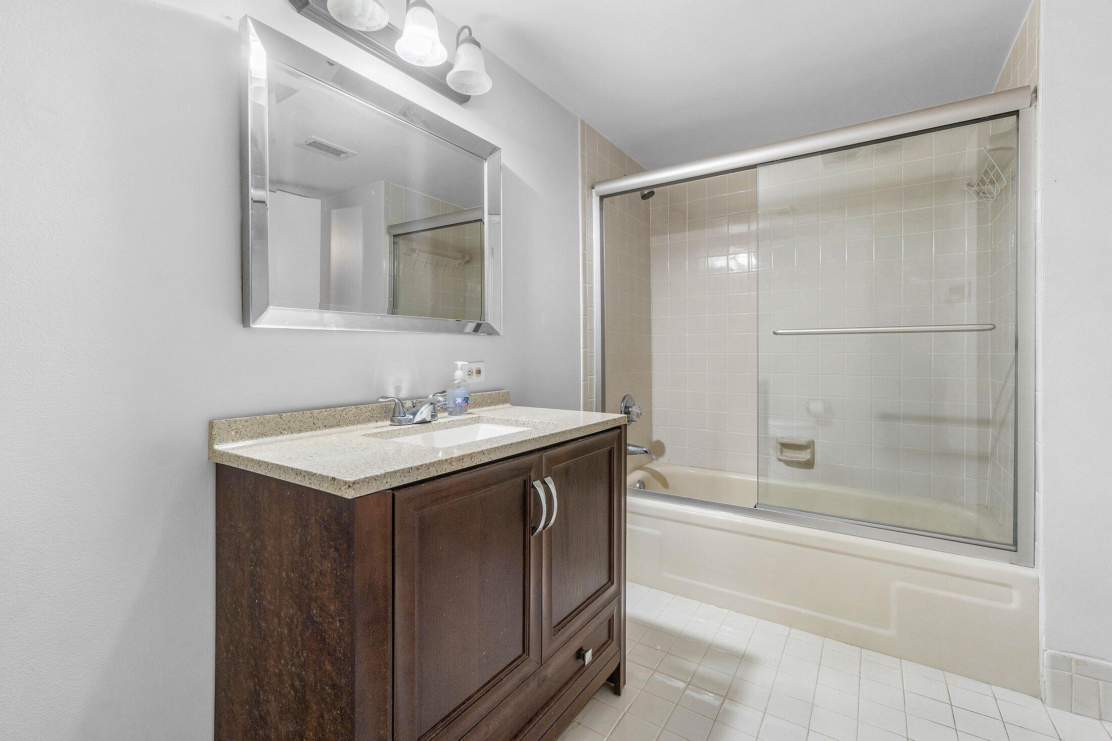 23395 Carolwood Lane, Unit 207 Boca Raton, FL 33428 - Photo 25 of 39 a bathroom with a granite countertop sink a mirror and a bathtub