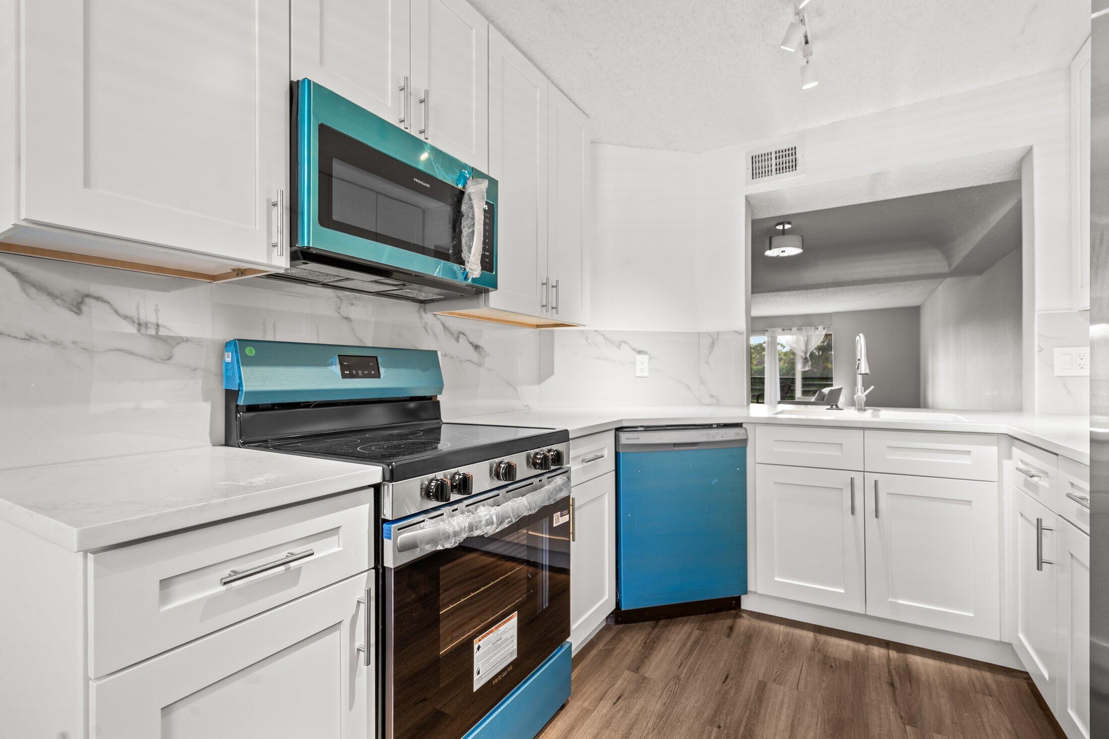 23395 Carolwood Lane, Unit 207 Boca Raton, FL 33428 - Photo 3 of 39 a kitchen with cabinets stainless steel appliances a sink and wooden floor