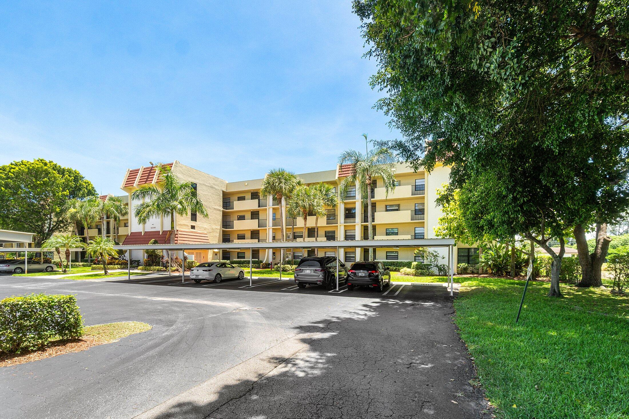 23395 Carolwood Lane, Unit 207 Boca Raton, FL 33428 - Photo 4 of 39 a building with trees in front of it