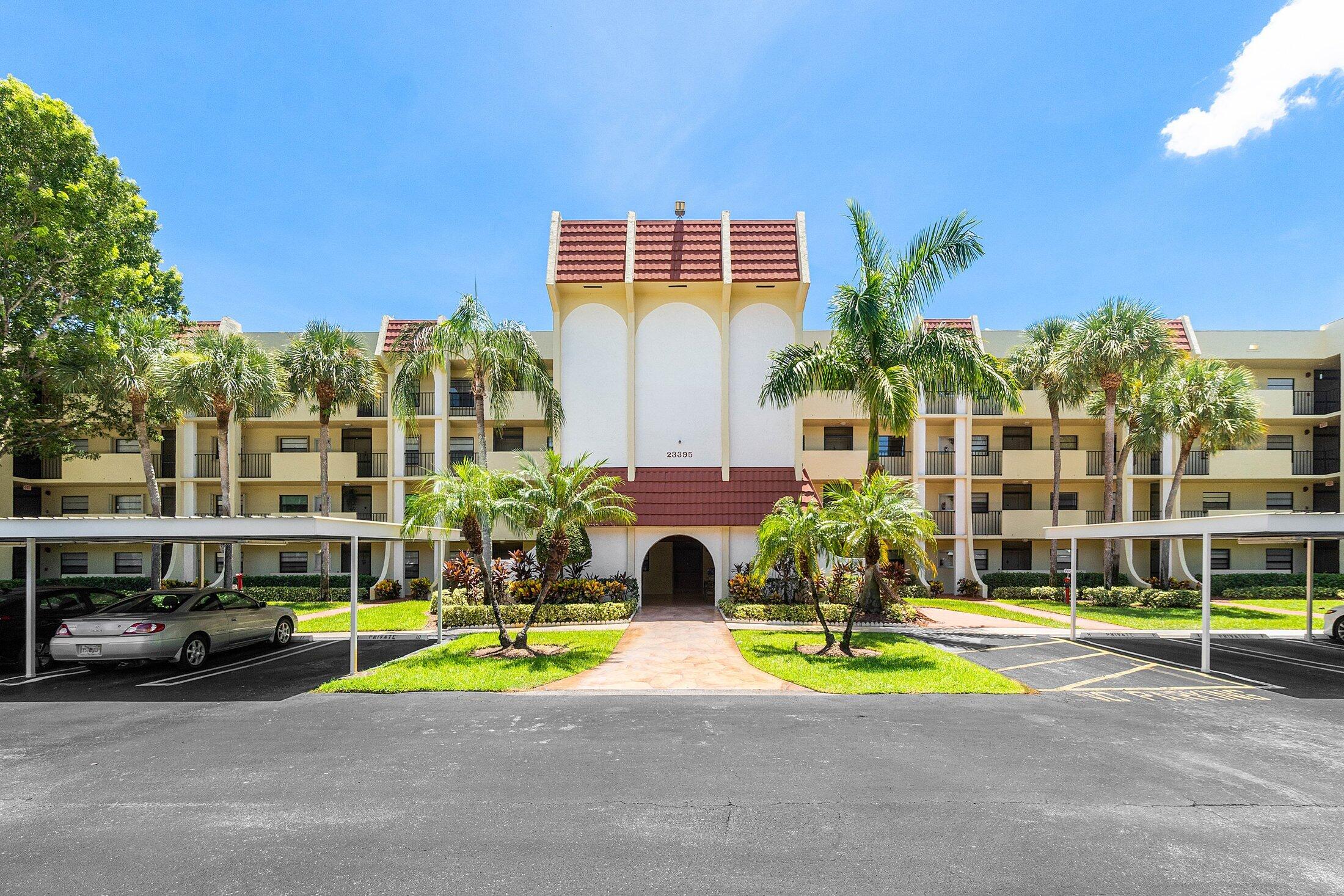 23395 Carolwood Lane, Unit 207 Boca Raton, FL 33428 - Photo 5 of 39 a view of a swimming pool with a lawn chairs and plants