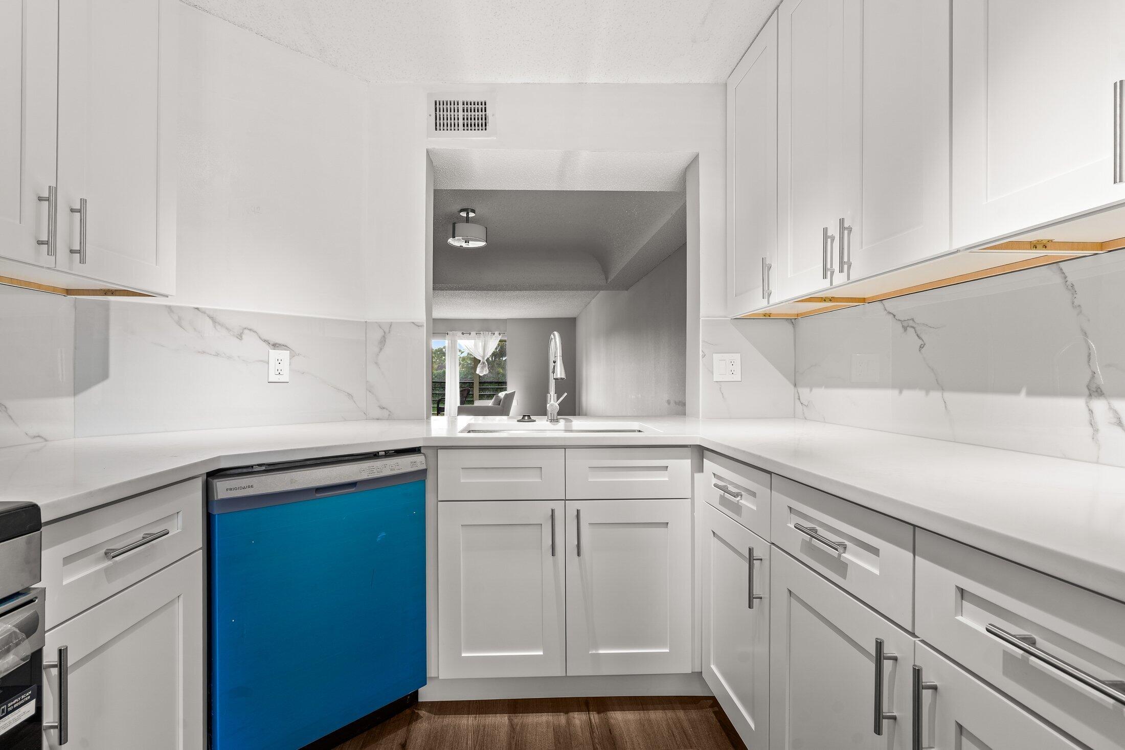 23395 Carolwood Lane, Unit 207 Boca Raton, FL 33428 - Photo 9 of 39 a kitchen with white cabinets and sink