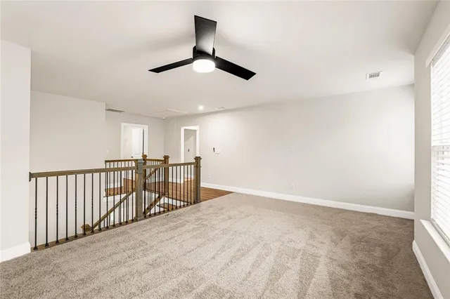 an empty room with ceiling fan and windows