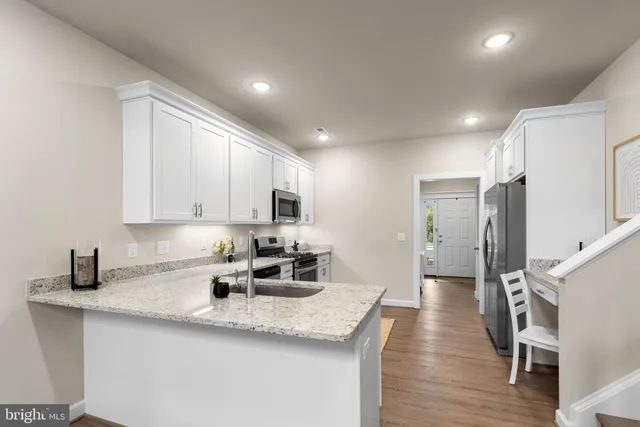 a view of a hallway with wooden floor and kitchen view