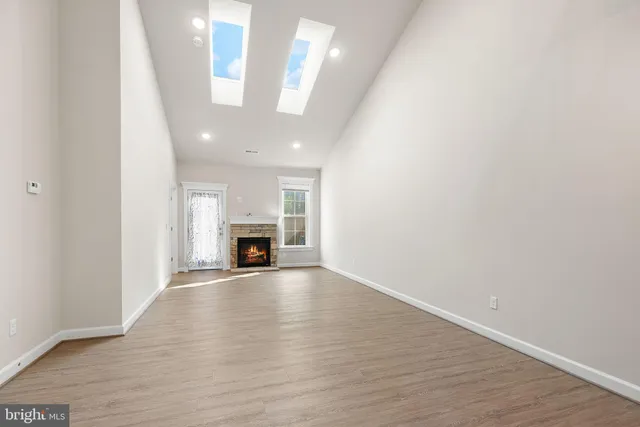 an empty room with wooden floor fireplace and windows