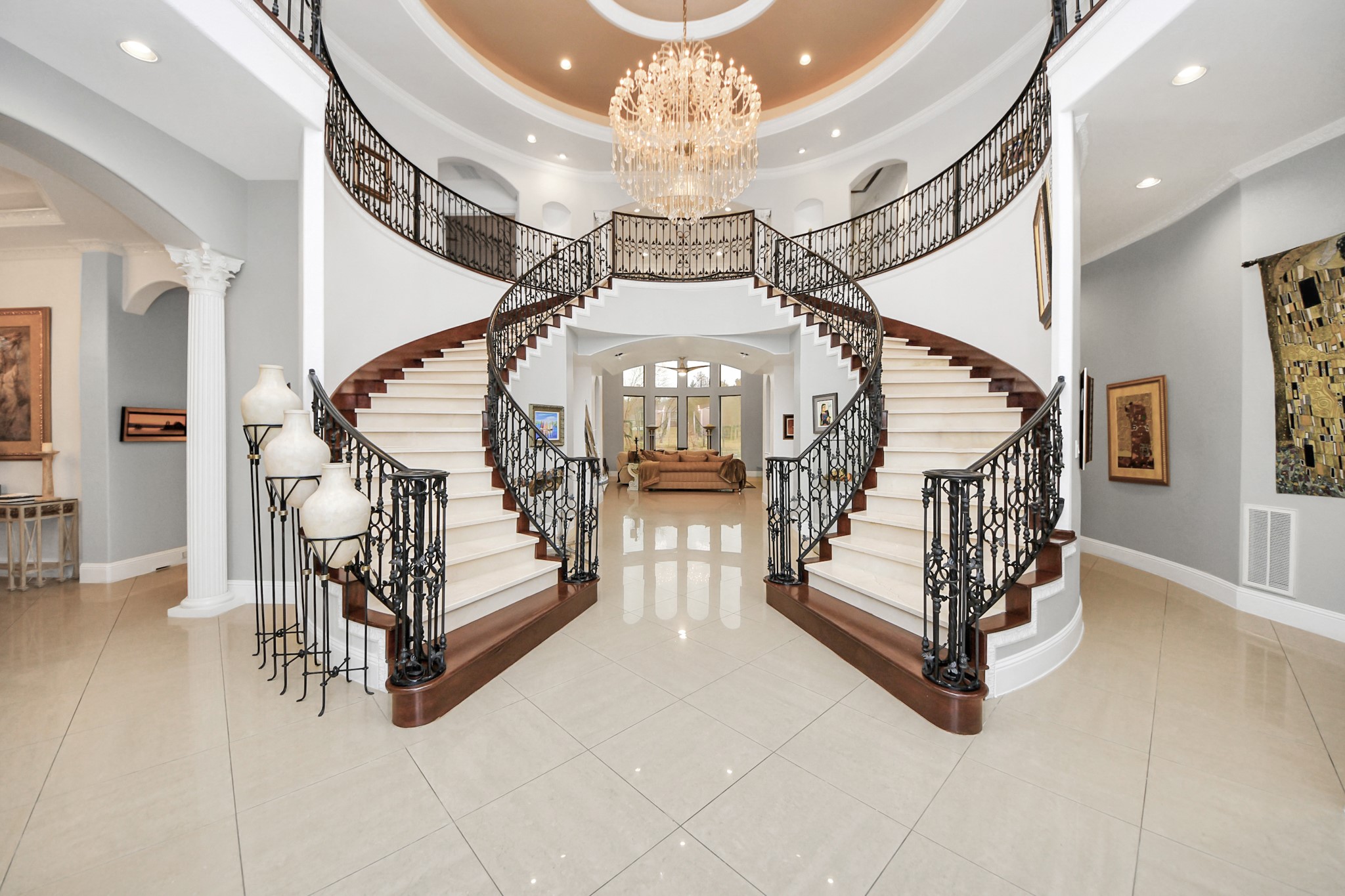 11503 Renaissance Drive Montgomery, TX 77356 - Photo 4 of 50 Impressive two-story foyer showcasing a sweeping double staircase, wrought-iron railings, and a dramatic domed ceiling with chandelier. The open design creates a striking sense of arrival and connects seamlessly to the main living areas.