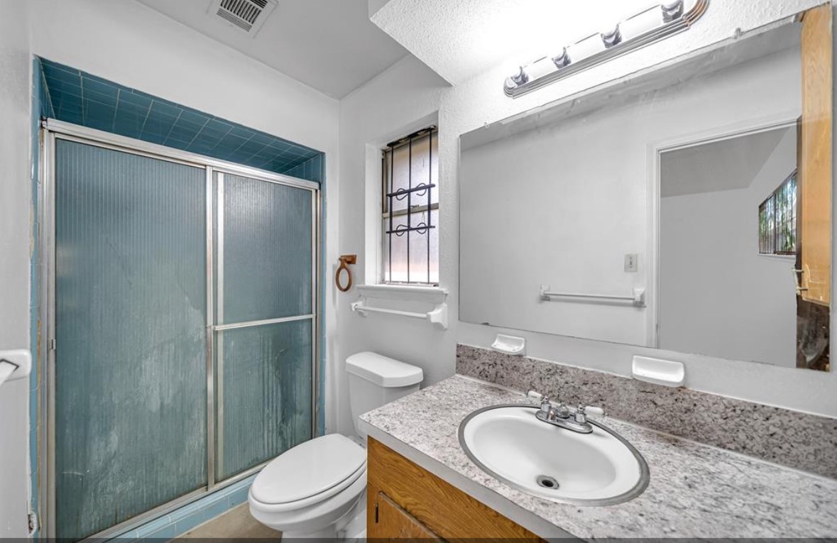 8447 Sterlingshire Street Houston, TX 77078 - Photo 24 of 26 a bathroom with a granite countertop sink toilet and shower