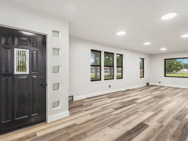 an empty room with wooden floor and windows