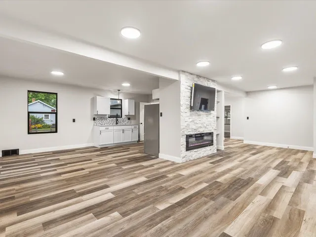 a view of a livingroom with a fireplace cabinet and windows