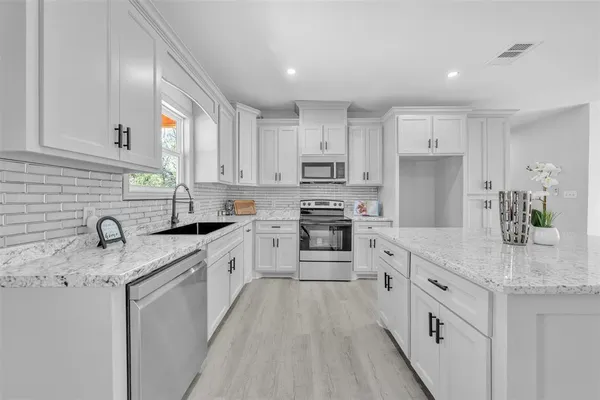 a kitchen with kitchen island granite countertop white cabinets white stainless steel appliances and sink