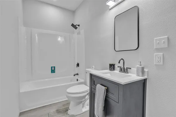 a bathroom with a toilet a sink a mirror and bathtub