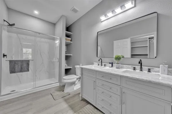 a bathroom with a double vanity sink toilet mirror and shower