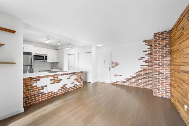 a large room with kitchen view wooden floor and stainless steel appliances