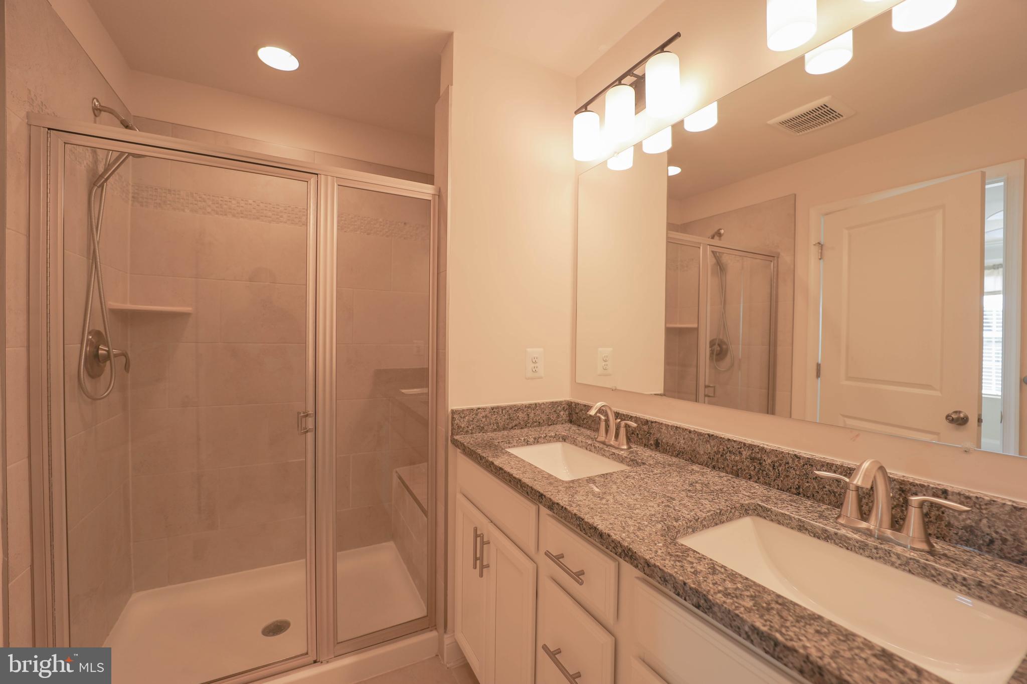 5054 Judicial Way Frederick, MD 21703 - Photo 21 of 28 a bathroom with a granite countertop sink a mirror and shower