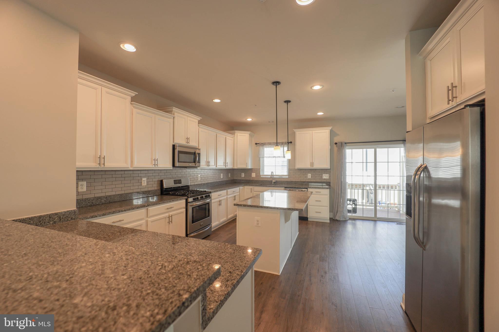 5054 Judicial Way Frederick, MD 21703 - Photo 7 of 28 a kitchen with stainless steel appliances granite countertop a refrigerator a sink dishwasher a stove and white countertops with wooden floor