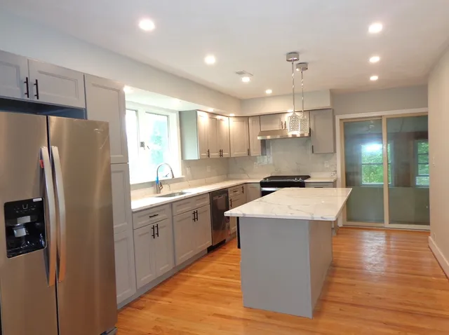 a kitchen with stainless steel appliances granite countertop a sink a refrigerator and a stove