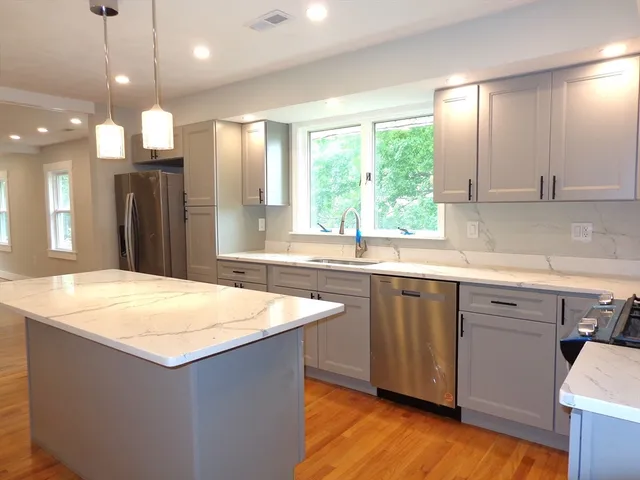 a kitchen with kitchen island granite countertop a sink a counter top space and appliances