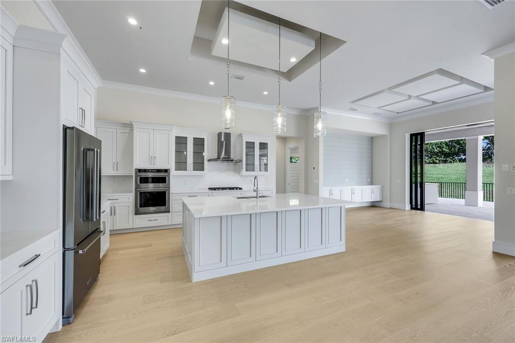 14282 Charthouse Circle Naples, FL 34114 - Photo 13 of 48 Kitchen with tasteful backsplash, glass insert cabinets, hanging light fixtures, white cabinets, and light stone countertops