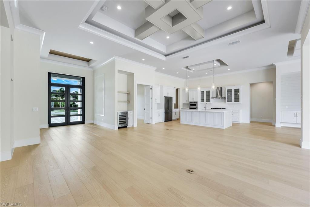 14282 Charthouse Circle Naples, FL 34114 - Photo 18 of 48 Unfurnished living room with light wood-style flooring, recessed lighting, coffered ceiling, wine cooler, and ornamental molding