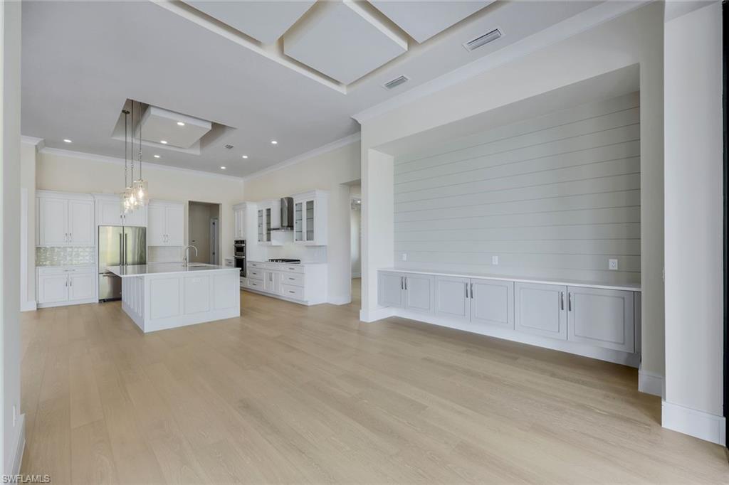 14282 Charthouse Circle Naples, FL 34114 - Photo 20 of 48 Unfurnished living room with crown molding, light wood-style flooring, a chandelier, and recessed lighting