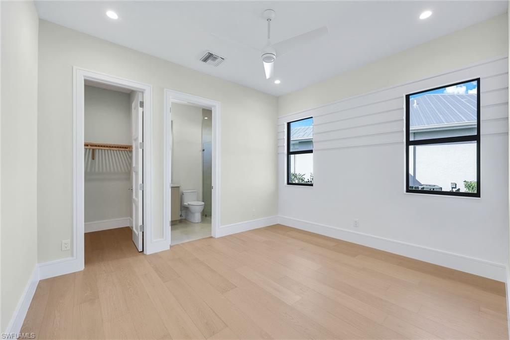 14282 Charthouse Circle Naples, FL 34114 - Photo 22 of 48 Unfurnished bedroom featuring a spacious closet, light wood-style floors, recessed lighting, and a ceiling fan