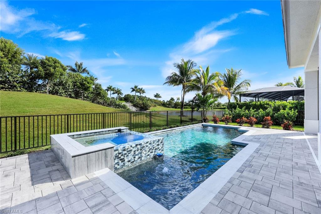 14282 Charthouse Circle Naples, FL 34114 - Photo 35 of 48 View of swimming pool featuring a patio area, a pool with connected hot tub, a fenced backyard, and a water view