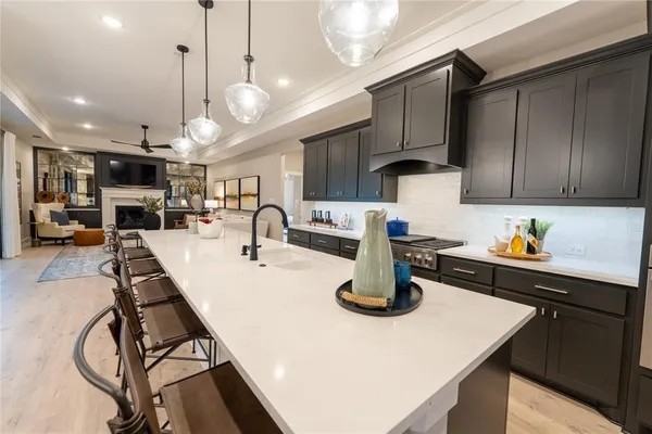 a kitchen with a sink a stove and chairs with wooden floor