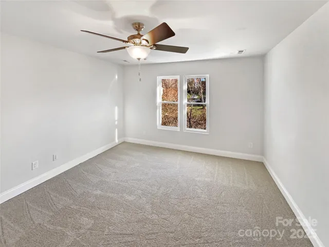 an empty room with windows and ceiling fan