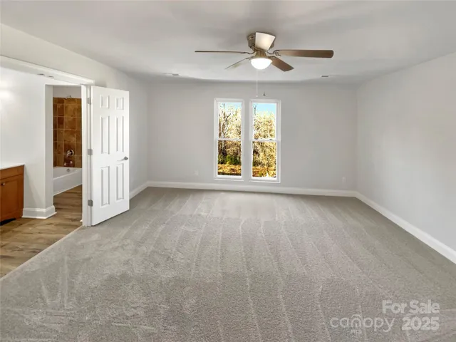 an empty room with windows and ceiling fan