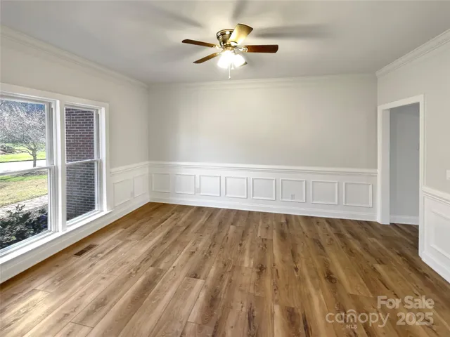 a view of an empty room with a window and wooden floor