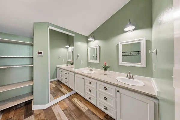 a spacious bathroom with double vanity a mirror and a shower