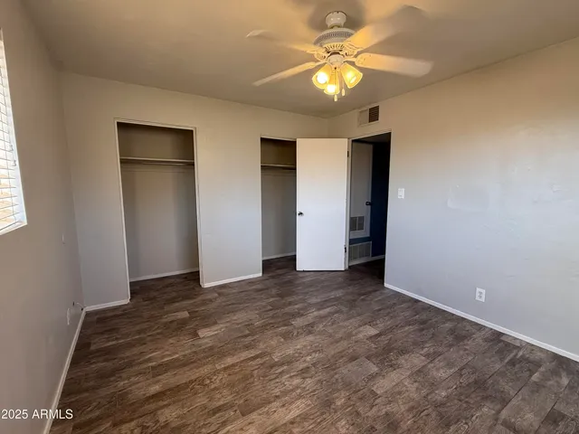an empty room with closet and a chandelier fan