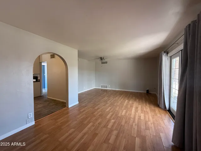 a view of empty room with wooden floor and fan