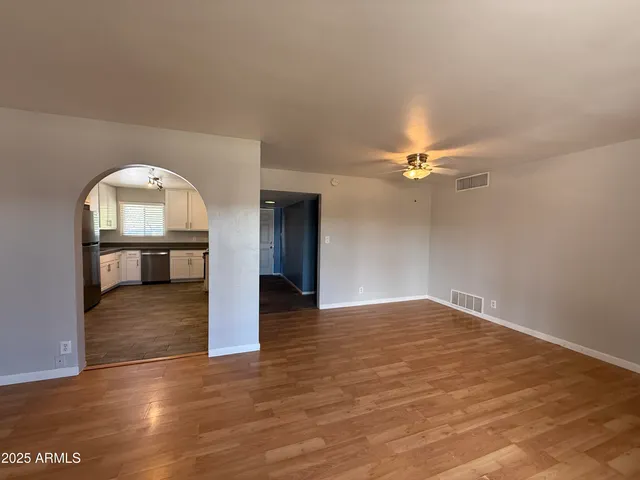 an empty room with wooden floor fan and windows