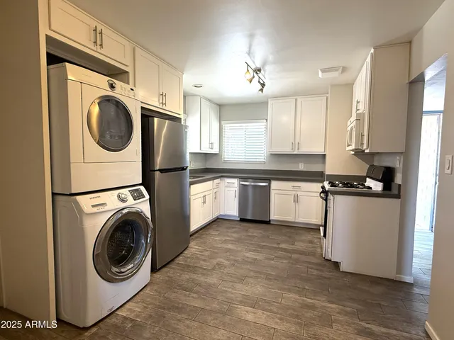 a kitchen with stainless steel appliances granite countertop a sink a stove a refrigerator cabinets and a window