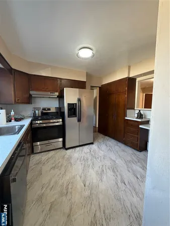 a kitchen with granite countertop a refrigerator and a stove top oven