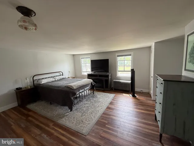 a spacious bedroom with a bed and wooden floor
